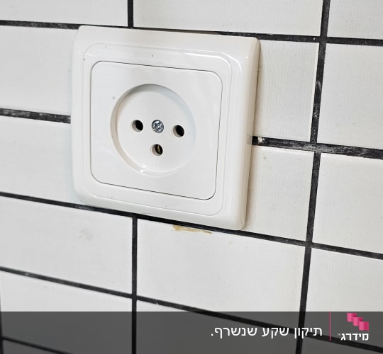 שקע חשמלי לבן מותקן על קיר מרוצף